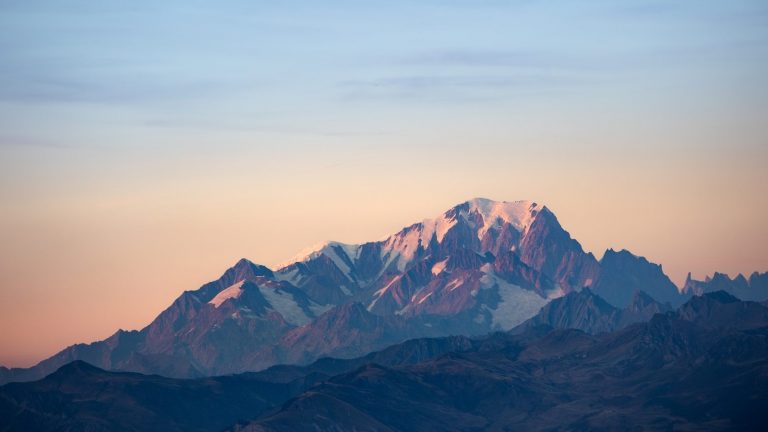 Snow-capped mountain range bathed in soft sunset light
